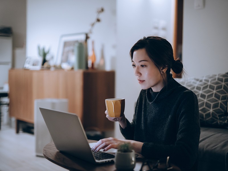 Women employee sitting with her laptop and coffee.